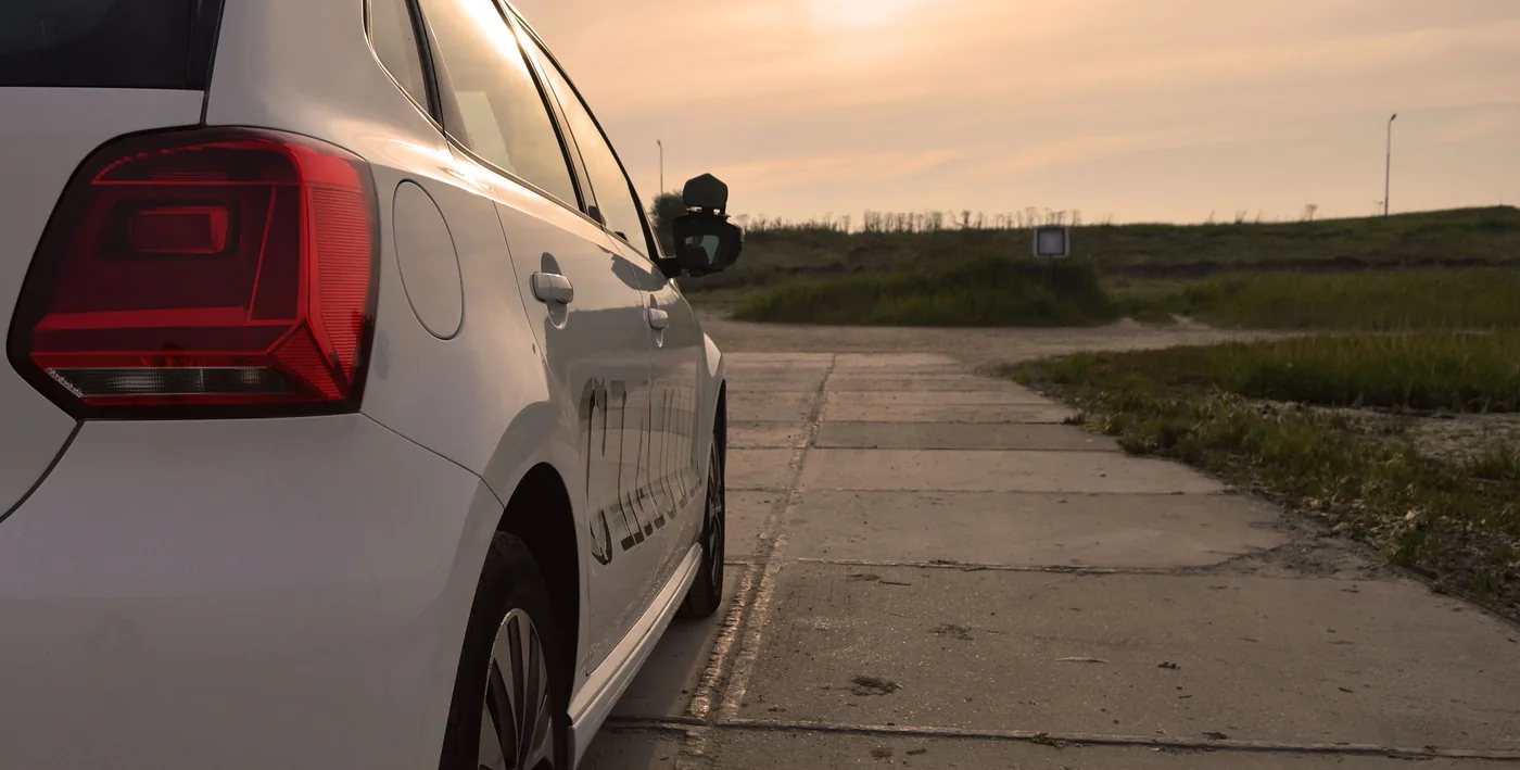 De witte lesauto in het warme licht van de ondergaande zon